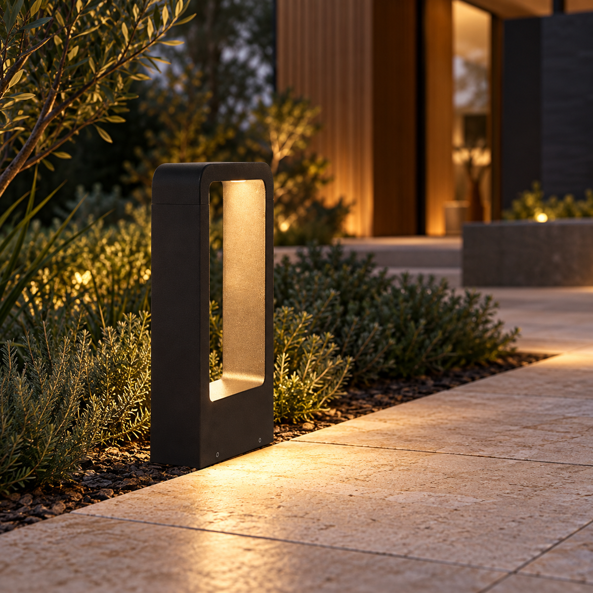Black open-frame LED bollard beside a stone garden path