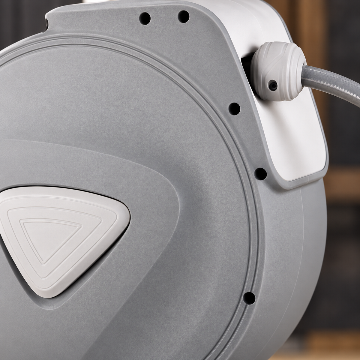 Close-up of the hose reel's grey casing, triangular inset, hose outlet and stopper.