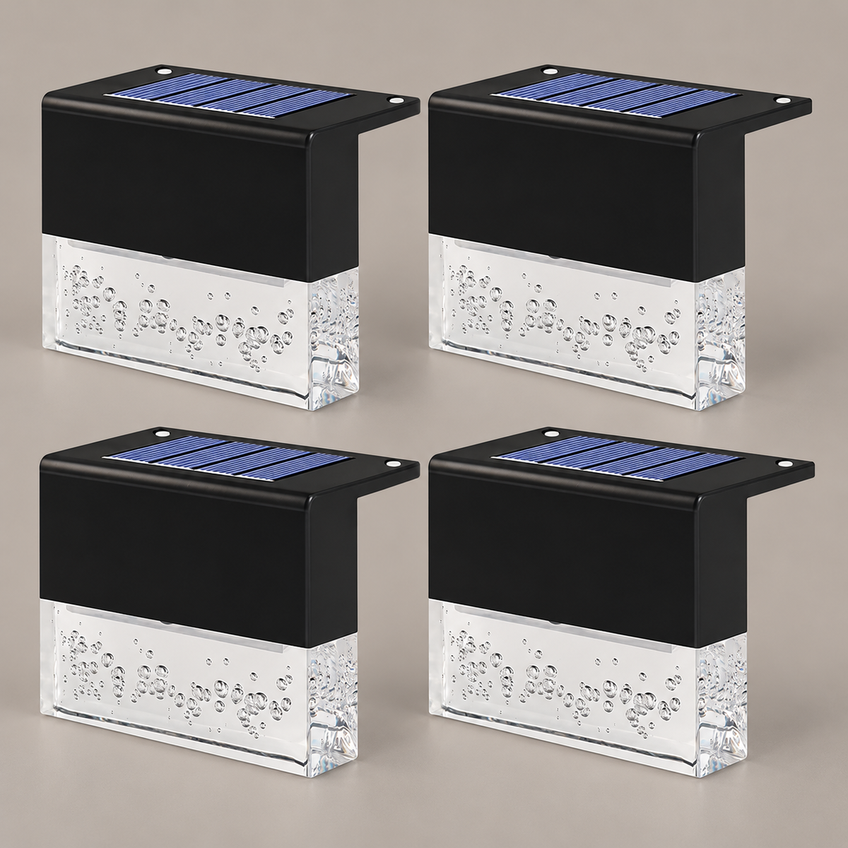 Set of four black solar deck lights with clear bubble diffusers on a taupe background