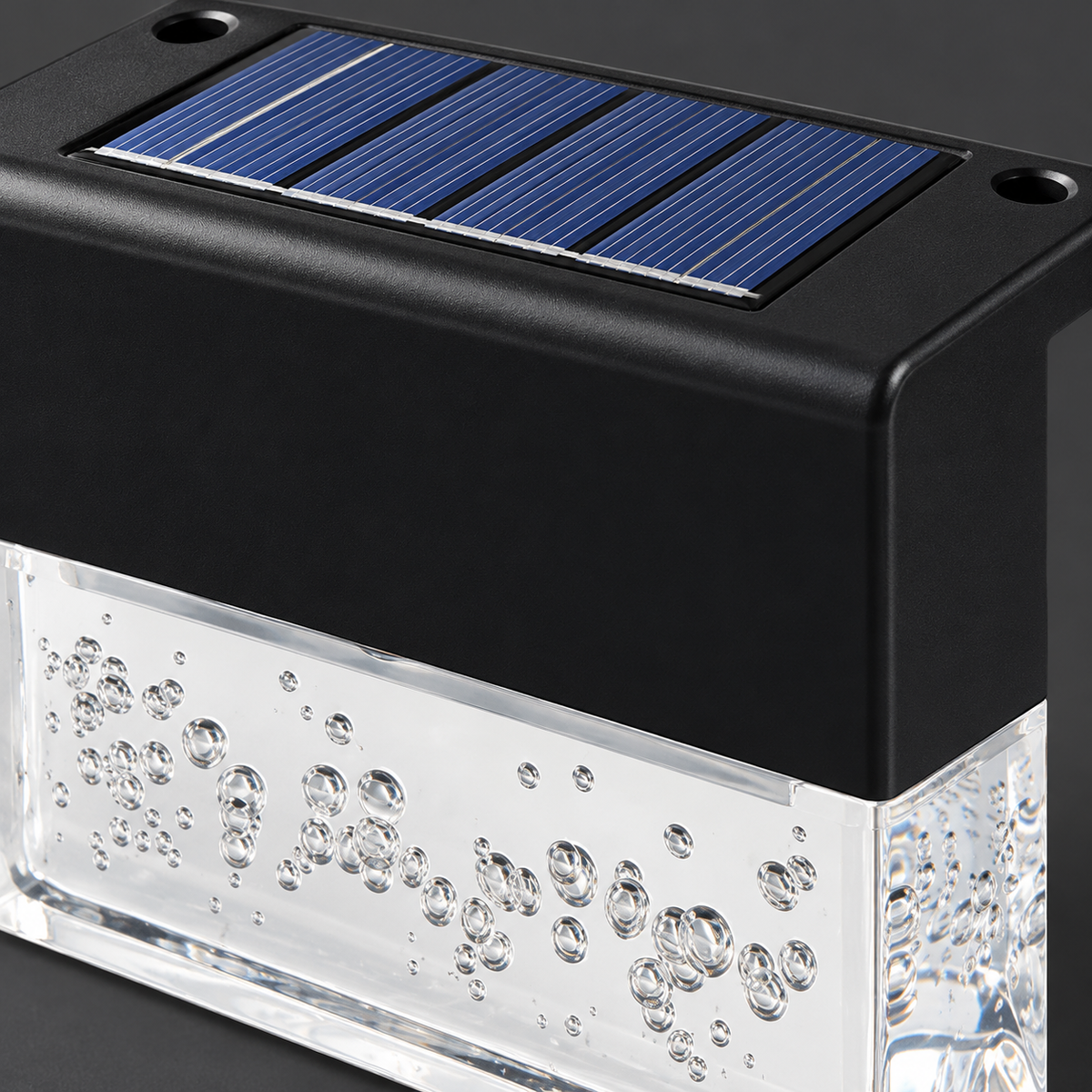 Close-up of a deck light solar panel, black housing and clear bubble diffuser