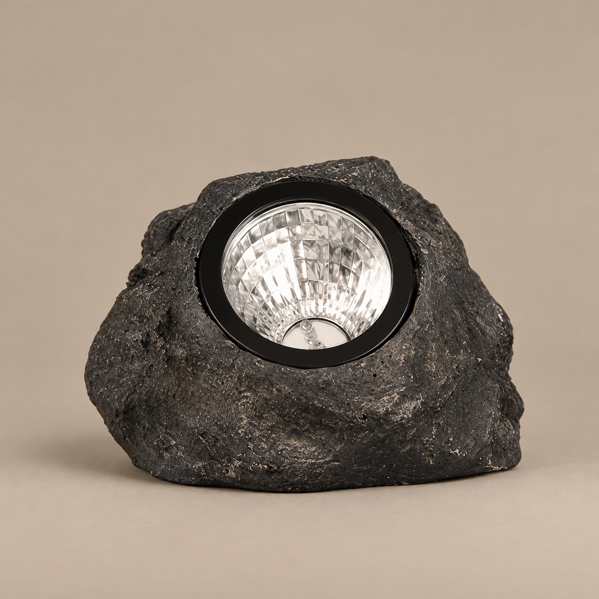 Black rock-style spotlight with circular reflector on a taupe background